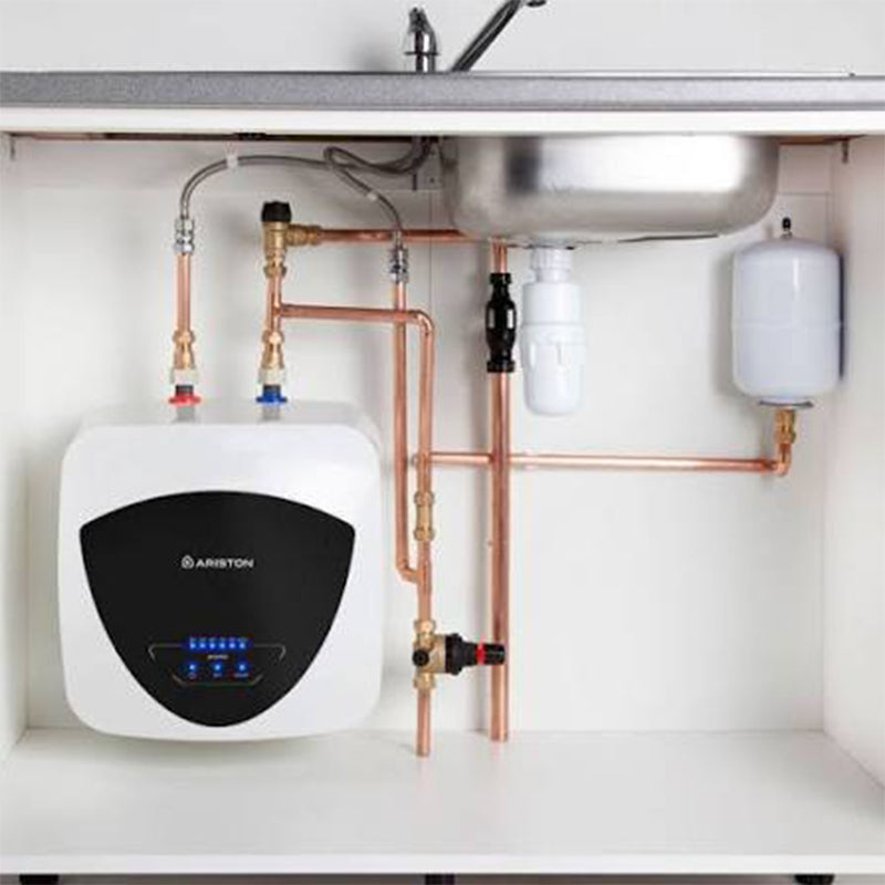 Ariston under-sink water heater system installed beneath a kitchen sink, with copper piping, a white water heater unit, a stainless steel sink basin, and a white pressure relief tank.